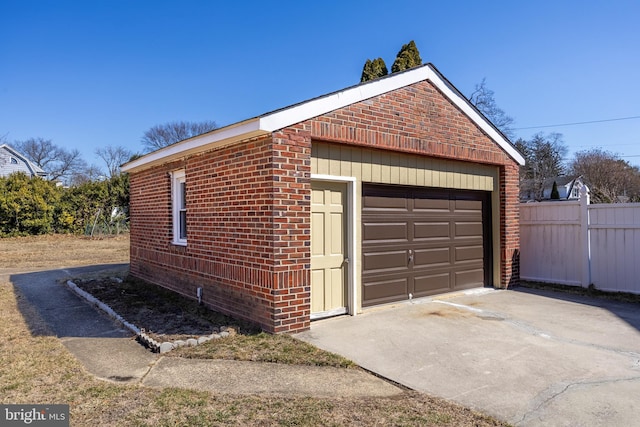 garage with concrete driveway and fence