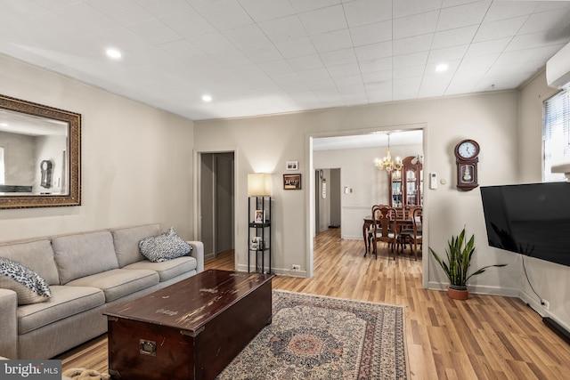 living area featuring recessed lighting, baseboards, light wood finished floors, and an inviting chandelier