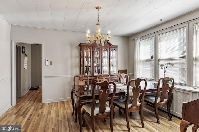 dining space featuring baseboards, light wood finished floors, and an inviting chandelier