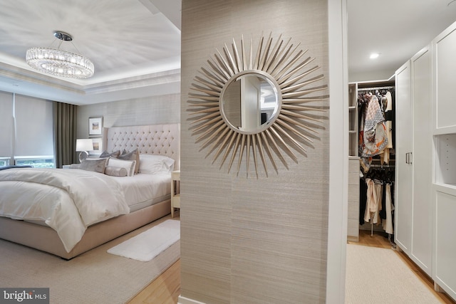 bedroom featuring light wood-style flooring, a closet, a walk in closet, and a notable chandelier