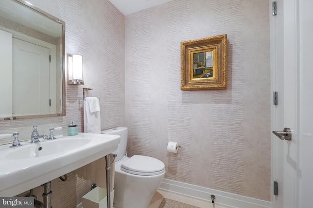 bathroom featuring a sink, a textured wall, and toilet