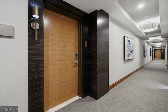 hallway with carpet, baseboards, and a tray ceiling