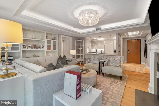 living area featuring light wood-style floors, a raised ceiling, visible vents, and a fireplace