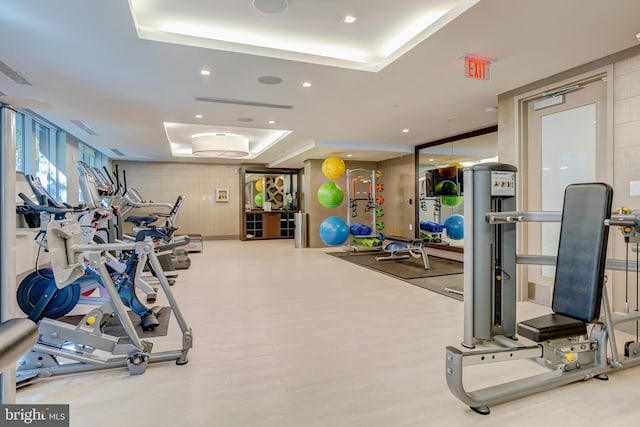 exercise room with a raised ceiling and recessed lighting