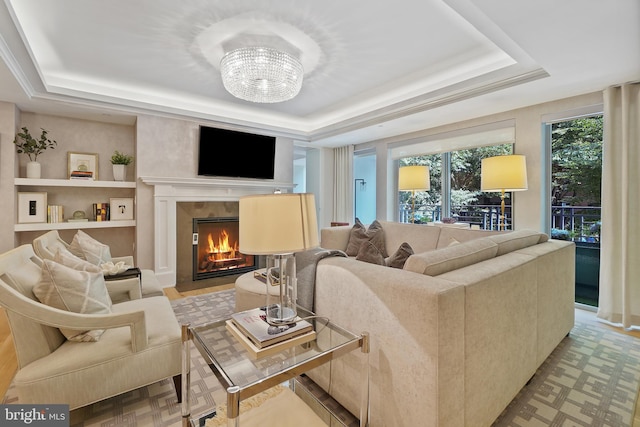 living room with a fireplace with flush hearth, a raised ceiling, and an inviting chandelier