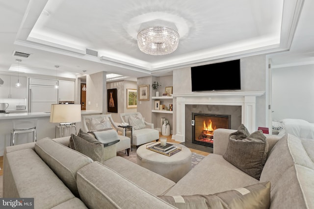 living room featuring a tray ceiling, visible vents, and a premium fireplace