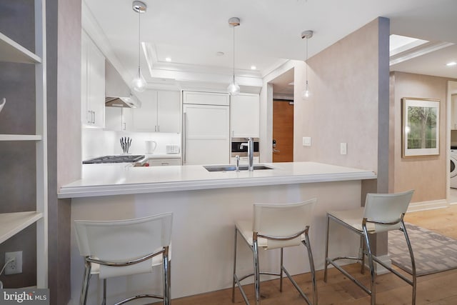 kitchen with a peninsula, a sink, white cabinetry, light countertops, and pendant lighting