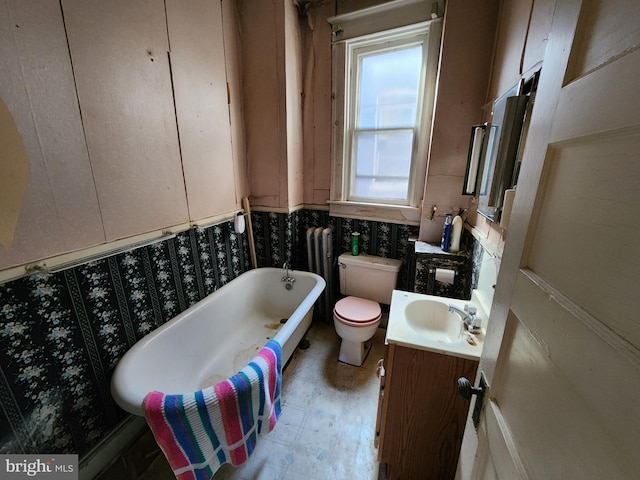 full bath featuring toilet, a soaking tub, and vanity