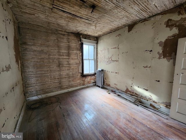 empty room with hardwood / wood-style floors and radiator heating unit