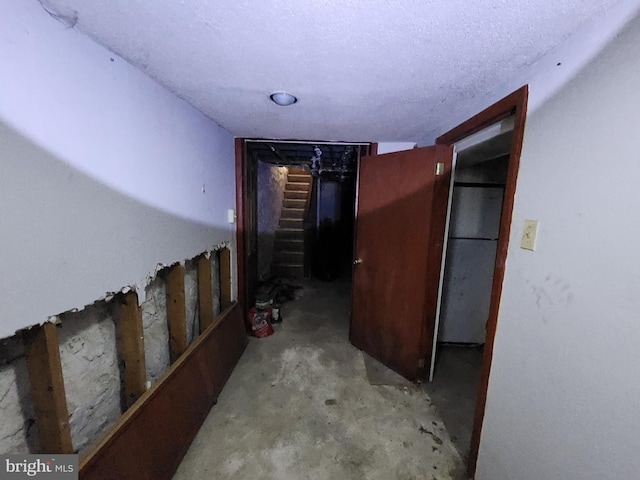 hall with stairs, concrete floors, and a textured ceiling