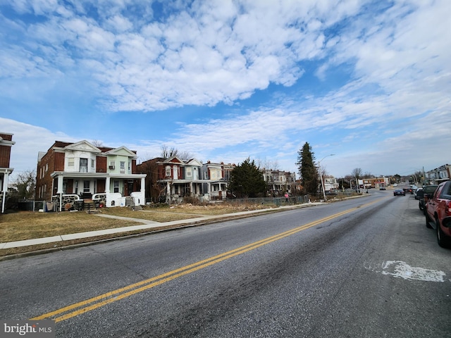 view of street with a residential view, curbs, sidewalks, and street lights