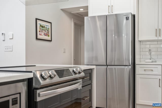 kitchen featuring tasteful backsplash, white cabinetry, stainless steel appliances, and light countertops