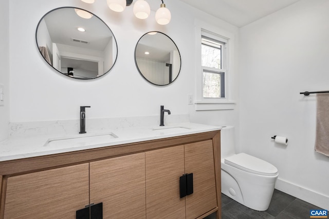 bathroom with toilet, double vanity, visible vents, and a sink