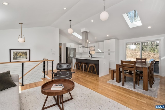 living area featuring lofted ceiling with skylight, light wood-type flooring, and recessed lighting