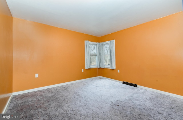 spare room featuring baseboards, visible vents, and carpet floors