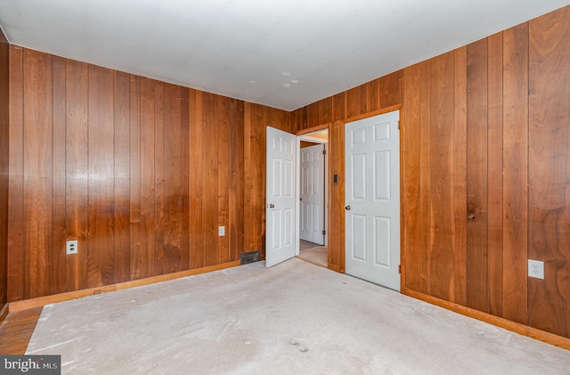 unfurnished bedroom with baseboards, wood walls, and carpet flooring