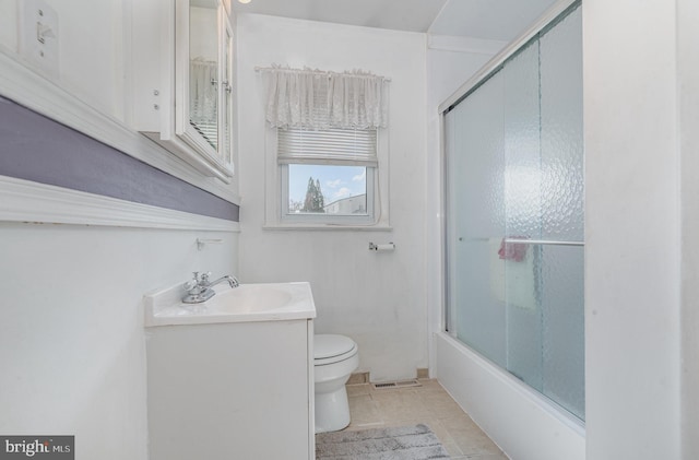 bathroom featuring visible vents, toilet, combined bath / shower with glass door, tile patterned flooring, and vanity