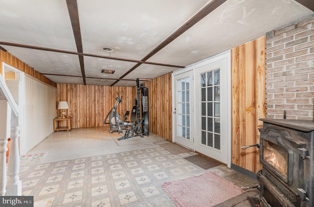 finished basement with tile patterned floors, wooden walls, and a wood stove