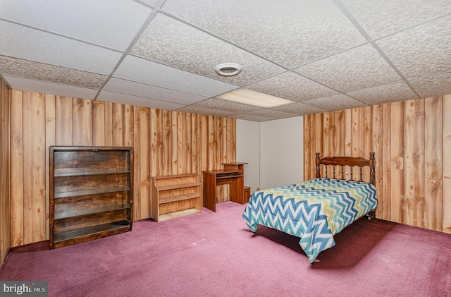 bedroom featuring a paneled ceiling, carpet floors, and wooden walls