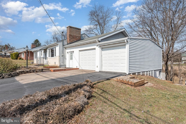 ranch-style house with a residential view, concrete driveway, a front yard, a chimney, and a garage