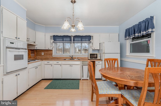 kitchen featuring white appliances, open shelves, a sink, under cabinet range hood, and a notable chandelier