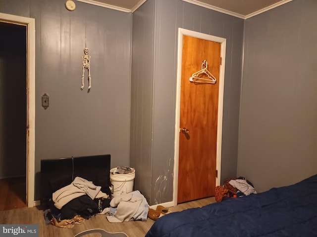 bedroom with ornamental molding and wood finished floors