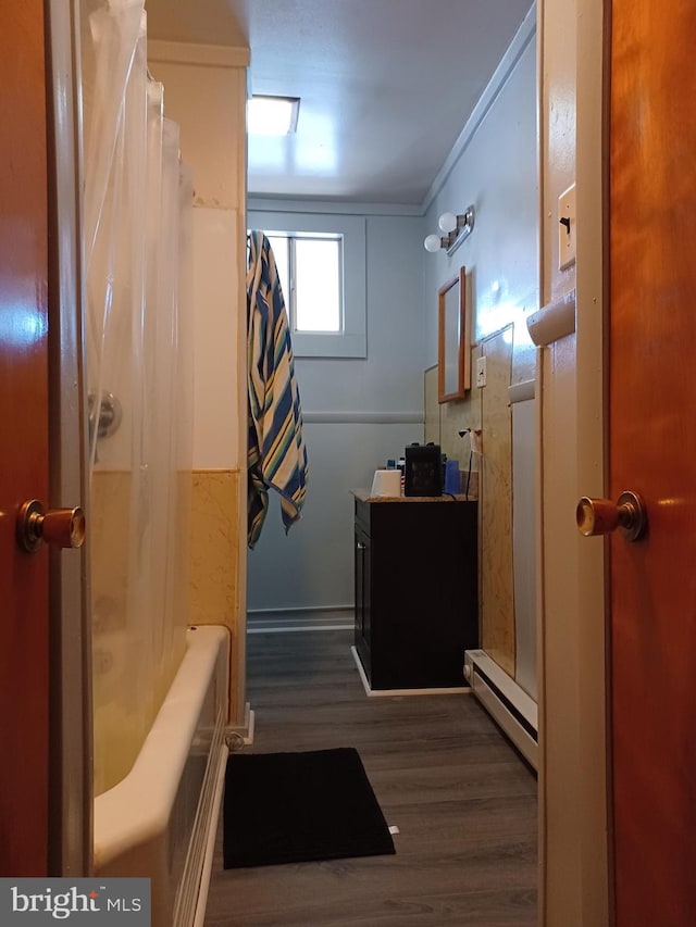 full bathroom featuring a baseboard radiator, wood finished floors, and vanity