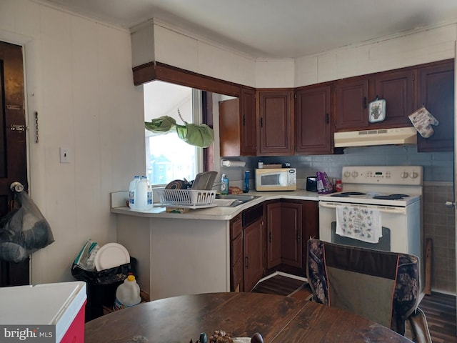 kitchen with tasteful backsplash, white appliances, light countertops, and under cabinet range hood