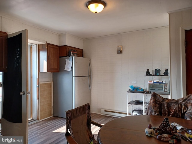 kitchen with freestanding refrigerator, baseboard heating, and wood finished floors