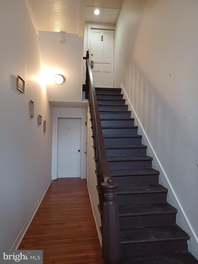 staircase featuring wood finished floors and baseboards