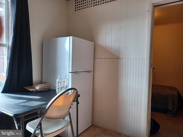 kitchen with freestanding refrigerator and wood walls