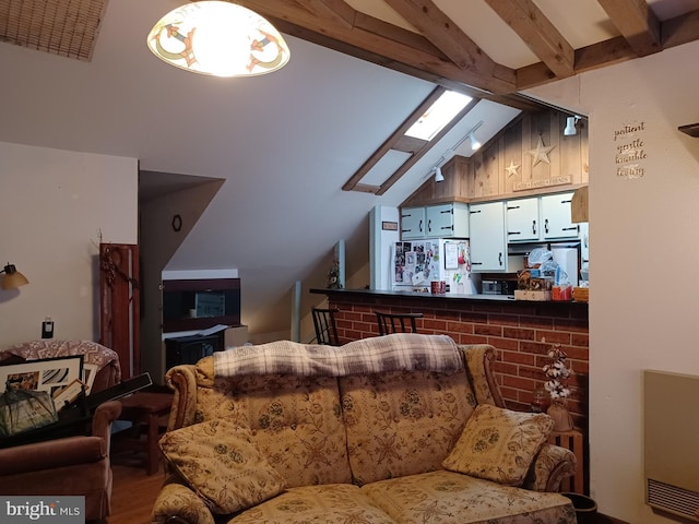 living area featuring lofted ceiling with skylight and wood finished floors