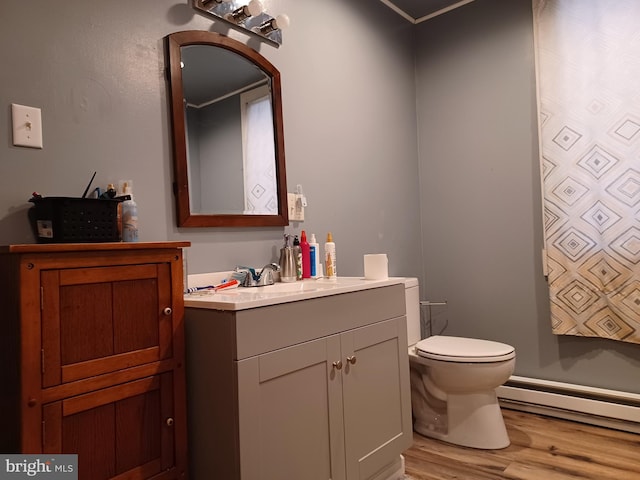 bathroom featuring toilet, baseboard heating, wood finished floors, and vanity