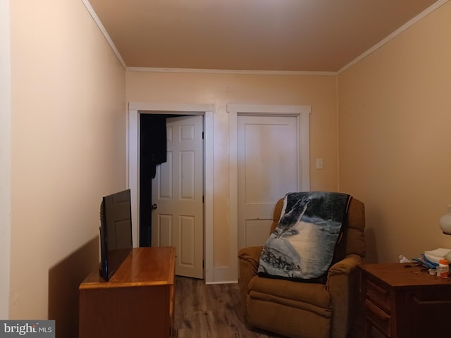 sitting room with ornamental molding and wood finished floors