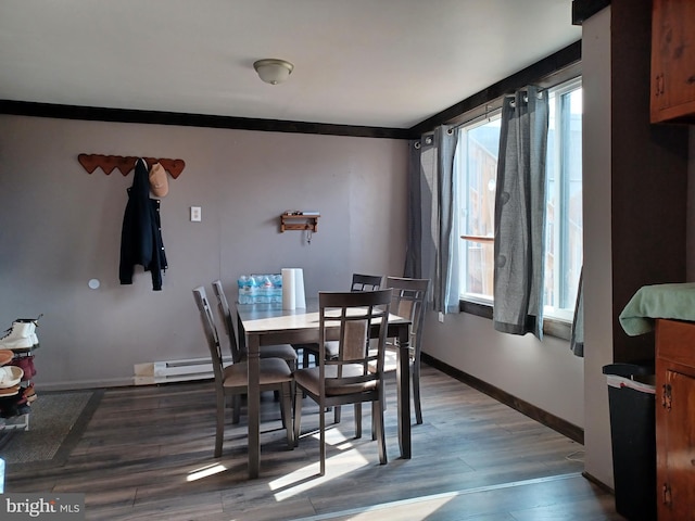 dining room featuring a baseboard heating unit, ornamental molding, wood finished floors, and baseboards