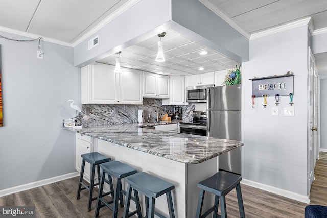 kitchen with visible vents, light stone countertops, ornamental molding, a kitchen breakfast bar, and stainless steel appliances