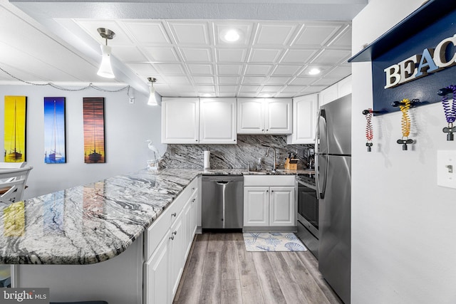 kitchen with light stone counters, appliances with stainless steel finishes, and a peninsula