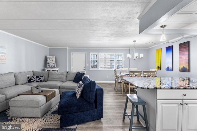 living area featuring ornamental molding, baseboards, an inviting chandelier, and wood finished floors