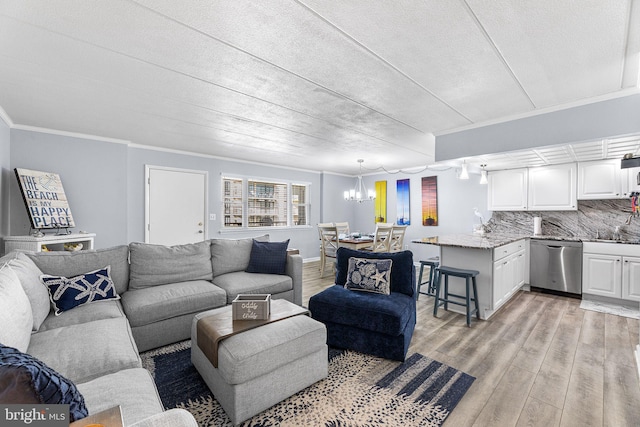 living room with crown molding, light wood-style floors, and an inviting chandelier