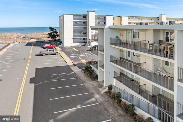 view of property with a beach view, a water view, and uncovered parking