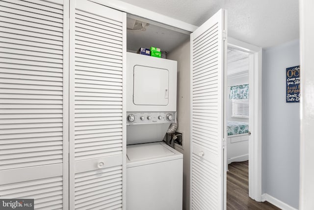 washroom featuring wood finished floors, baseboards, laundry area, a textured ceiling, and stacked washer / dryer