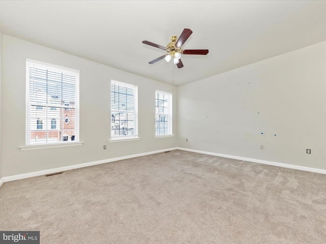 carpeted empty room with a ceiling fan, visible vents, and baseboards