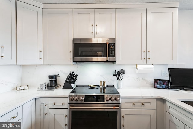 kitchen with white cabinets, tasteful backsplash, and stainless steel appliances