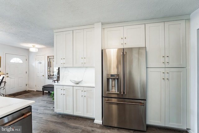 kitchen featuring white cabinets, high quality fridge, dark wood-type flooring, a textured ceiling, and backsplash