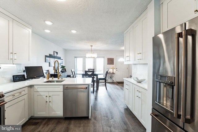 kitchen with a peninsula, white cabinetry, appliances with stainless steel finishes, and a sink