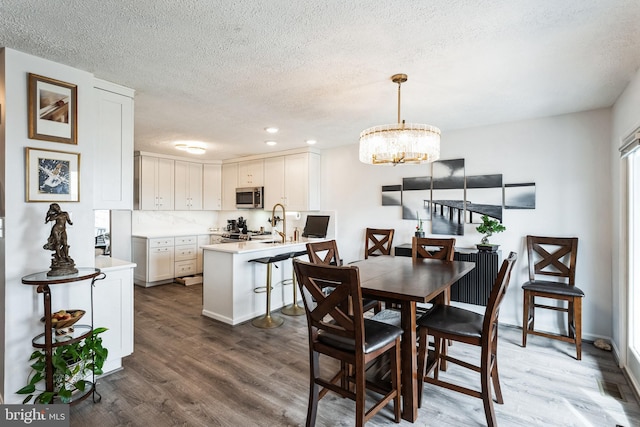 dining space with a chandelier, dark wood finished floors, a textured ceiling, and recessed lighting