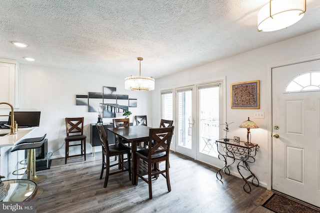 dining room with a notable chandelier, a textured ceiling, baseboards, and wood finished floors