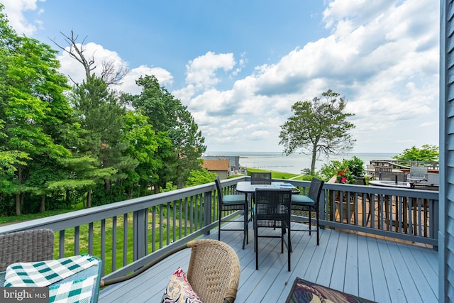 deck with a water view and outdoor dining space