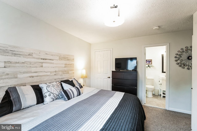 bedroom with carpet flooring, connected bathroom, and a textured ceiling