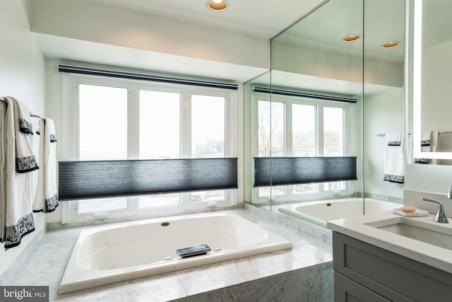 bathroom with a garden tub and vanity